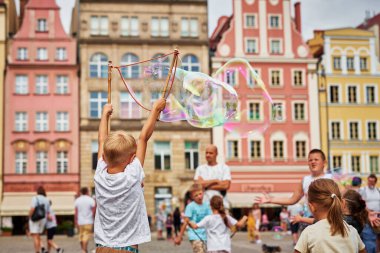 Çocuk şehir sokaklarında büyük kabarcıklar yapıyor.
