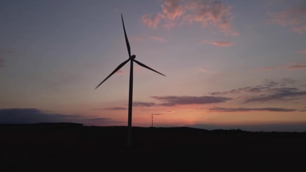 Silhueta de turbina de moinho de vento no campo ao pôr do sol céu. Gerador de vento rotativo — Vídeo de Stock