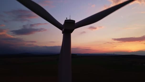Sylwetka turbiny wiatrowej na polu o zachodzie słońca. Obrotowy generator wiatru — Wideo stockowe