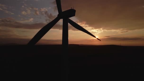 Silhueta de turbina de moinho de vento no campo ao pôr do sol céu. Gerador de vento rotativo — Vídeo de Stock