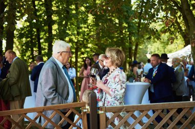 Yaşlı adam ve kadın dışarıda konuşuyor ve şarap içiyor.