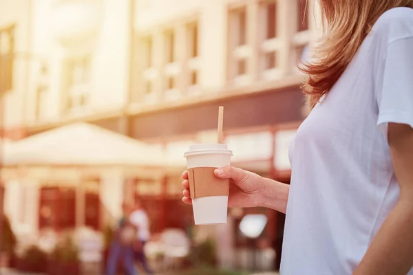 Vrouw houdt papieren koffiekop op straat — Stockfoto