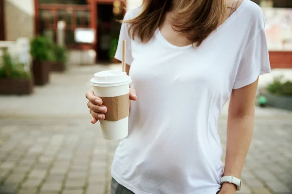 Mulher segura xícara de café de papel na rua da cidade — Fotografia de Stock