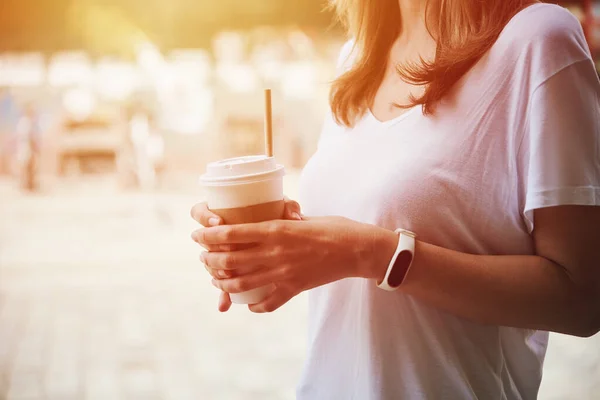 Mulher segura xícara de café de papel na rua da cidade — Fotografia de Stock