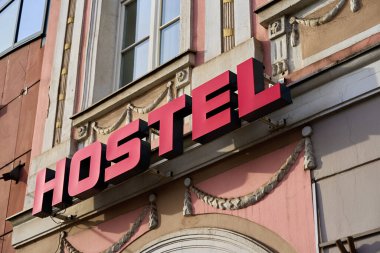 Şehir caddesindeki tarihi bina cephesinde kırmızı pansiyonun yakın çekimi. Seyahat, turizm ve şehir konaklama kavramı