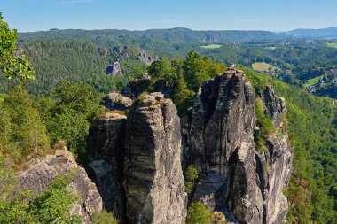 Panoramic view of sandstone cliffs and green forest under clear blue sky in Saxon Switzerland National Park, Germany. Natural landscape