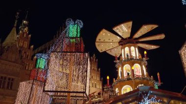 Christmas fair at night with illuminated gifts and festive carousel in historic city center. Festive Christmas market in Wroclaw, Poland. Concept of holiday celebration, winter tradition and tourism