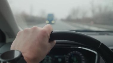 Kırsaldaki sisli otoyolda sürücünün direksiyon tutuş şeklinin yakın görüntüsü. Araba kullanan kişi, içeriden gören. Yol güvenliği ve ulaşım kavramı