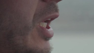 Konuşurken çenesi ve ağzı sakallı adamın yakın görüntüsü. Kişinin hareketli dudaklarla konuşma süreci