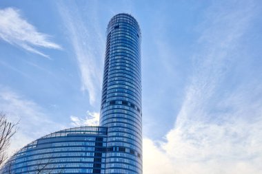Güneş ışığını ve mavi gökyüzünü yansıtan kavisli cepheli modern cam gökdelen. Wroclaw, Polonya 'daki Sky Tower binası. Çağdaş mimari