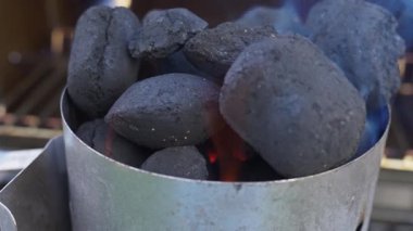 Metal ızgaranın içinde yanan kömür briketlerinin yakın çekimi. Barbekü hazırlığı ve açık hava pişirme konsepti