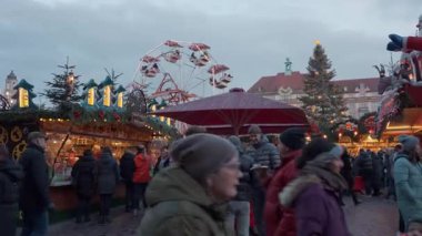 İnsanlar alacakaranlıkta süslü Noel pazarında festival ışıkları ve tezgahlarıyla yürüyorlar. Tatil geleneği, Avrupa kültürü ve mevsimsel seyahat kavramı. Dresden, Almanya - 24 Aralık 2024