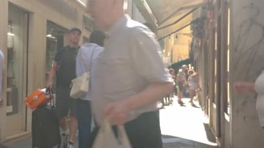 Dar bir sokakta yürüyen turistler, tarihi binalarla eski, güneşli Avrupa şehrinde. Şehir turizmi, tatil ve yaz seyahati yaşam tarzı kavramı. Venedik, İtalya - 27 Ağustos 2025