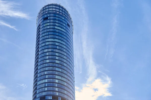 Kıvrımlı, uzun, cam gökdelenin alçak açılı görüntüsü. Mavi gökyüzüne karşı ofis binası. Çağdaş mimari tasarım