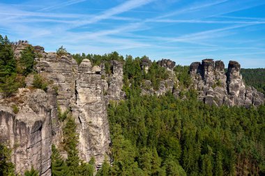 Panoramic view of sandstone cliffs and green forest under clear blue sky in Saxon Switzerland National Park, Germany. Natural landscape