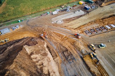 Kazı makineleri ve kamyonlarla inşaat alanının havadan görüntüsü. Toprak, lojistik depo inşa etmeden önce çalışır. Geliştirme, mühendislik ve altyapı kavramı