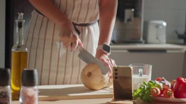 Mutfaktaki tahta tahtada tereyağlı kabak kesen önlüklü bir adam. Masada taze sebze ve otlarla taze balkabağı dilimleyen bir kadının yakın çekimi. Sağlıklı beslenme ve ev yemeği kavramı