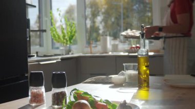 Önlüklü bir kadın, mutfak masasına sebze ve tereyağlı kabak koyuyor. Kızartma için balkabağı ve sebze hazırlayan kişi. Ev yemeği ve sağlıklı beslenme kavramı