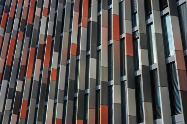 Dikey renkli panelleri ve dar dikey pencereleri olan modern bir ofis binasının cephesi. Gökdelenin dış tarafı. Çağdaş mimari tasarımı