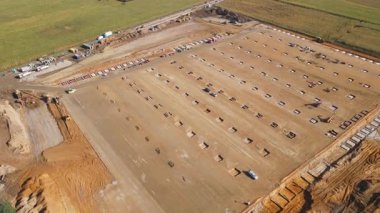 Beton temeller ve toprak ağır makinelerden oluşan büyük bir inşaat alanının havadan görüntüsü. Yeni bir lojistik deposu inşa ediyorum. Mühendislik, altyapı ve geliştirme kavramı