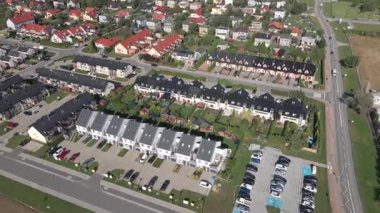 Güneşli bir günde şehir merkezinde evleri, bahçeleri ve park halindeki arabaları olan modern konut manzarası. Sıra sıra kasaba evleri olan modern yerleşim yerleri