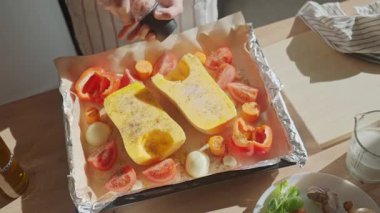 Mutfağa tereyağlı kabak ve sebze serpiştiren kişi. Taze kabak ve sebzeleri pişirmek için biber öğütücü kullanan eller. Ev yemeği ve sağlıklı yemek hazırlama kavramı