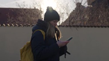 Kadın şehir caddesinde yürürken akıllı telefon kullanıyor. Navigasyon, iletişim, teknoloji ve şehir yaşam tarzı kavramı