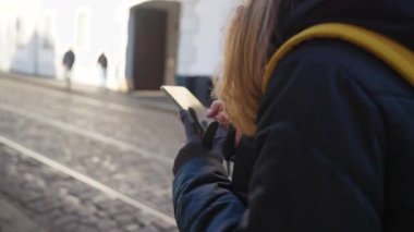 Kadın şehir caddesinde yürürken akıllı telefon kullanıyor. Navigasyon, iletişim, teknoloji ve şehir yaşam tarzı kavramı