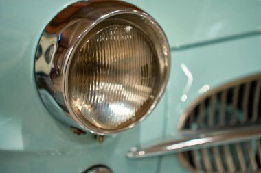 Izgarası, farları ve krom tamponu olan mavi bir arabanın ön tarafı. Klasik otomobil parçaları ve klasik araç tasarımı