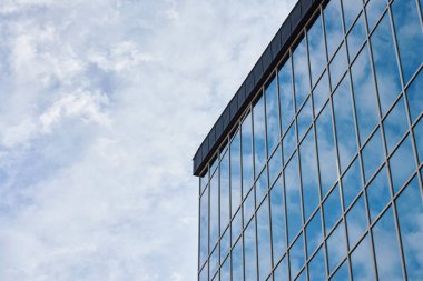 Gökyüzünü yansıtan büyük pencereli modern ofis binasının cam cephesi. Çağdaş mimari tasarım