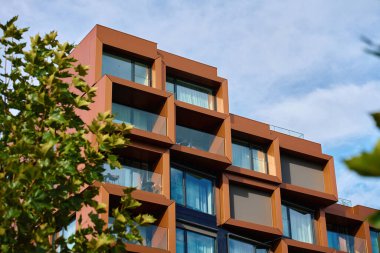 Geometrik pencere çerçeveleri ve cam balkonları olan modern apartman cephesi. Çağdaş mimari