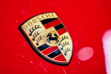 Kırmızı bir arabanın kaputunda Porsche amblemi var. Otomotiv markası ve araç tasarımı. Wroclaw, Polonya - 4 Aralık 2022