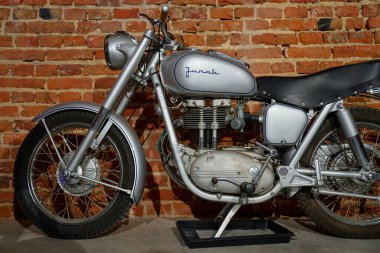 Gümüş renkli bir Junak motosikletinin yan görüntüsü. Tekerlekleri, motoru, koltuğu ve yakıt deposu tuğla duvarın önünde. Wroclaw, Polonya - 4 Aralık 2022