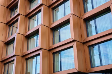 Modern bina cephesi, geometrik metal paneller ve geniş yansıtıcı pencereler. Çağdaş mimari, şehir dışı ve ticari mülkiyet tasarımı kavramı.