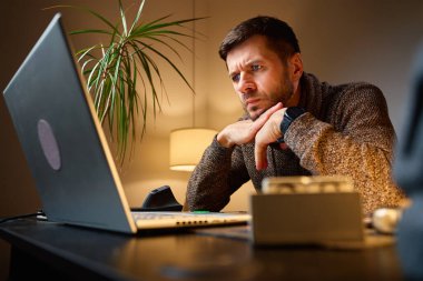Masasında lambayla oturup dizüstü bilgisayara bakan yorgun bir adam. Ofiste geç saatlere kadar çalışan biri. Stres kavramı, tükenme ve uzak işlerde aşırı çalışma