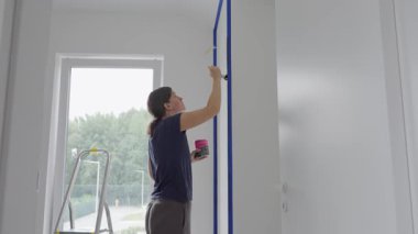 Modern odadaki pencerenin yanında kadın iç duvarı fırçayla boyuyor. Ev yenileme, iç boyama ve DIY onarım kavramı.