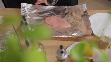 Mutfak tezgahında kurutulmuş bitkilerle çiğ tavuk filetosu soslayan ellerinizi kapatın. Ev yemeği, yemek hazırlama ve sağlıklı ev yemeği kavramı..