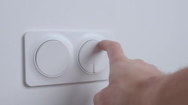 İç duvardaki modern beyaz ışık düğmesine, kapalı mekan ışıklarını açmak için yakın plan. Elektrik kullanımı, ev denetimi ve enerji tüketimi kavramı