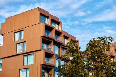 Geometrik pencere çerçeveleri ve cam balkonları olan modern apartman cephesi. Çağdaş mimari