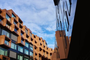 Açısal metal panelleri ve yansıtıcı cam yüzeyleri olan modern bina cepheleri. Çağdaş mimari, geometrik tasarım ve kentsel gelişim kavramı.