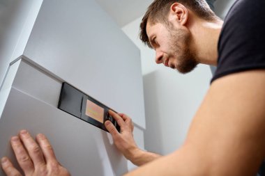Kurulum sırasında modern evdeki ısı pompasının kontrol panelini ayarlayan adam. Ev ısıtma, enerji verimliliği ve havalandırma bakımı kavramı