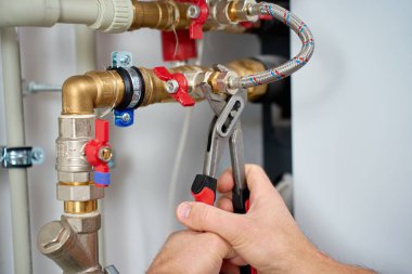 Vana ve esnek hortumla uyumlu tesisatı sıkmak için ayarlanabilir anahtarı kullanarak ellerinizi kapatın. Tesisat, bakım ve ev mühendisliği kavramı.