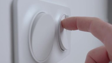 İç duvardaki modern beyaz ışık düğmesine, kapalı mekan ışıklarını açmak için yakın plan. Elektrik kullanımı, ev denetimi ve enerji tüketimi kavramı