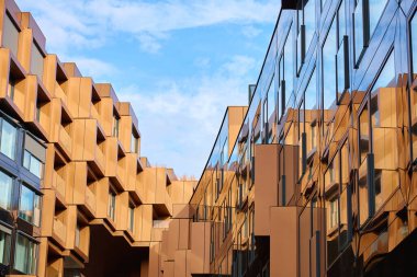 Açısal metal panelleri ve yansıtıcı cam yüzeyleri olan modern bina cepheleri. Çağdaş mimari, geometrik tasarım ve kentsel gelişim kavramı.