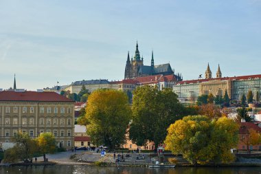 Prag Kalesi 'nin panoramik manzarası ve Prag' daki Vltava Nehri boyunca kırmızı çatıları olan tarihi binalar. Seyahat, miras ve Avrupa mimarisi kavramı. Prag, Çek Cumhuriyeti - 20 Ekim 2025