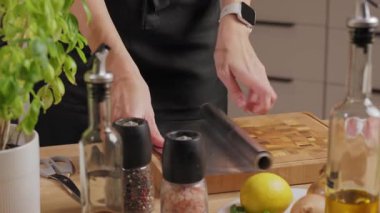 Ev mutfağındaki ahşap kesme tahtasına alüminyum folyo döken kadın ellerine yakın çekim. Yemek hazırlama ve pişirme süreci kavramı