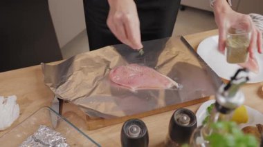 Mutfak tezgahında kurutulmuş bitkilerle çiğ tavuk filetosu soslayan ellerinizi kapatın. Ev yemeği, yemek hazırlama ve sağlıklı ev yemeği kavramı..