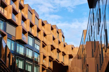 Açısal metal panelleri ve yansıtıcı cam yüzeyleri olan modern bina cepheleri. Çağdaş mimari, geometrik tasarım ve kentsel gelişim kavramı.