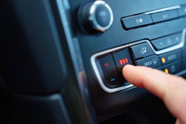 Aracın gösterge panelindeki ısıtmalı koltuk düğmesine kırmızı ışıklarla yakın çekim. Soğuk havada sıcaklık ayarlama ve sürüş konforu kavramı