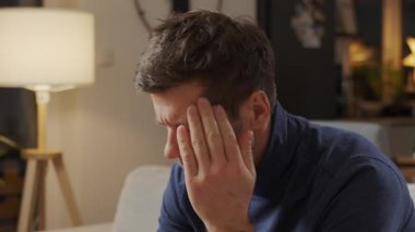 Adam oturma odasında kanepede otururken kırmızı hap içip su içmekten acı çekiyor. Ağrıyı dindirmek için ilaç alan kişi. İlaç, sağlık ve tedavi kavramı